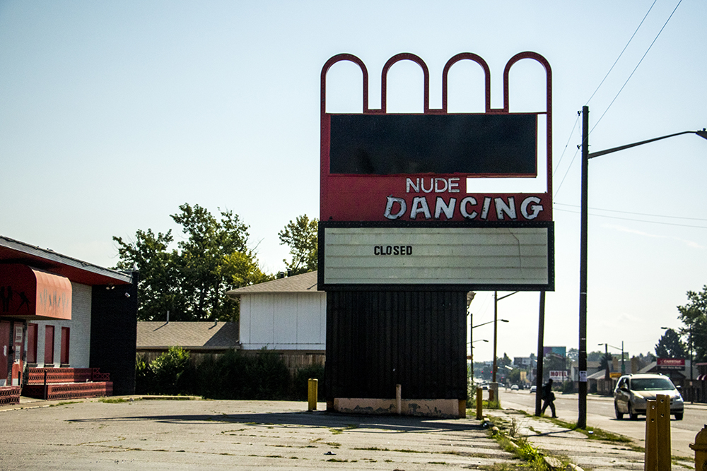 A film photograph of a road-side strip club sign which reads 